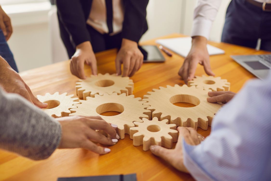Team members fitting wooden gears together on a table